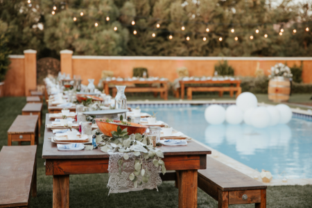 Backyard wedding with long dinner table set up near the pool.